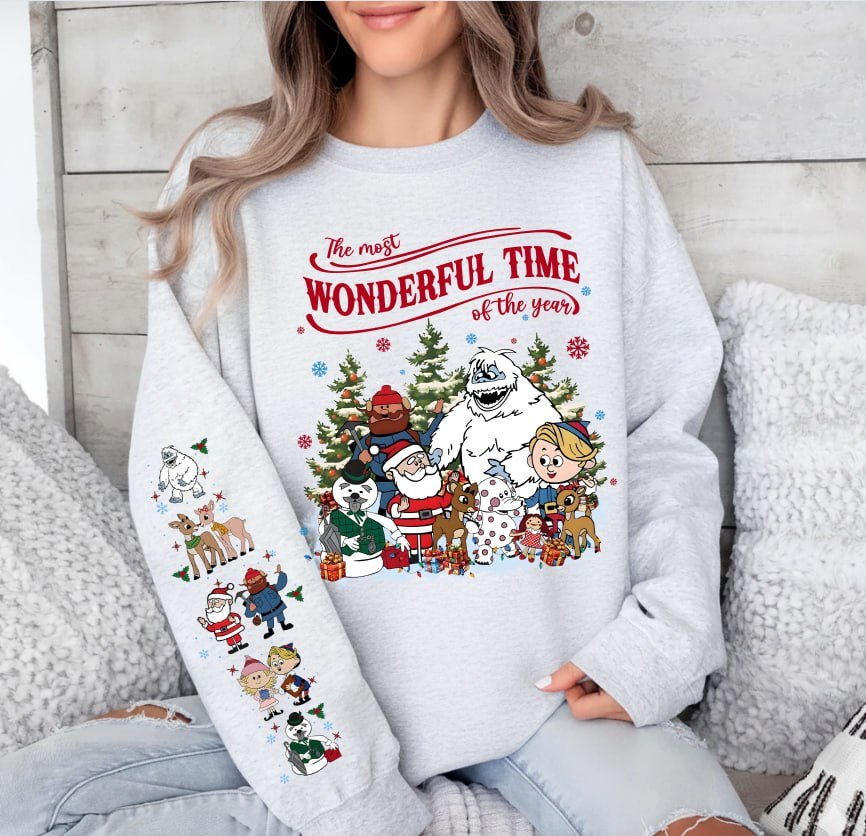 Beige retro Rudolph The Red-Nosed Reindeer Christmas hoodie with sleeve prints, featuring Bumble, Santa, and "The most wonderful time of the year" quote