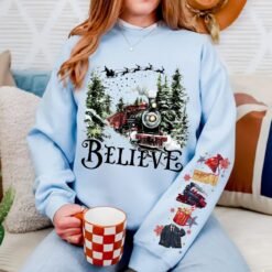 Black Christmas sweatshirt featuring a vintage train in a snowy forest with the word Believe, and Polar Express themed sleeve prints like a golden ticket and hot cocoa