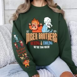 Light grey retro Christmas sweatshirt featuring Heat Miser and Snow Miser, Miser Brothers Heating and Cooling graphic, and character sleeve prints