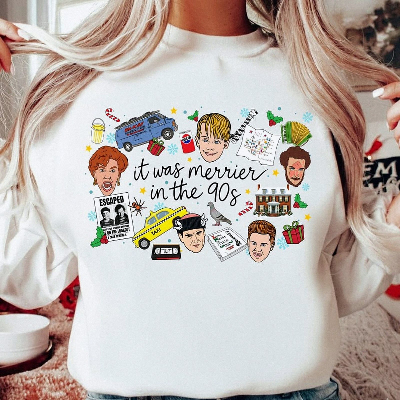White crewneck Christmas sweatshirt featuring a retro 90s holiday movie collage design with the text "it was merrier in the 90s" alongside nostalgic characters and icons