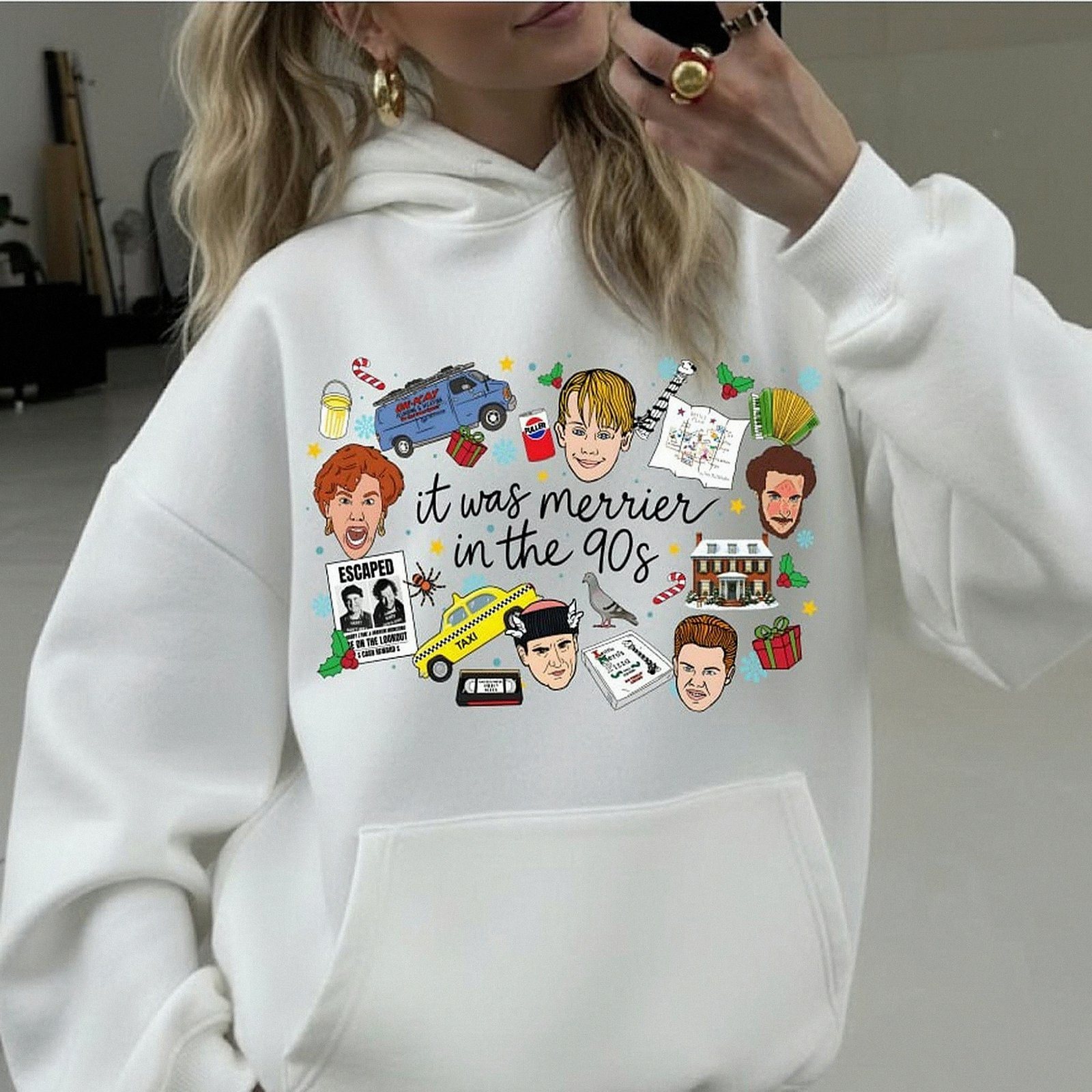 White crewneck Christmas sweatshirt featuring a retro 90s holiday movie collage design with the text "it was merrier in the 90s" alongside nostalgic characters and icons